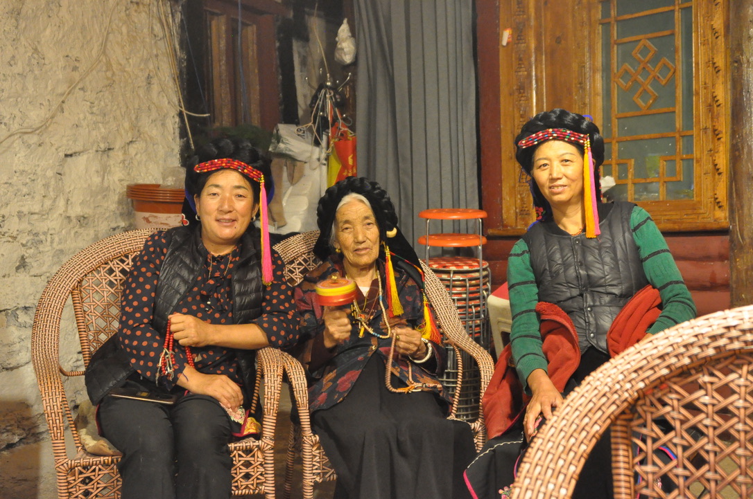 Three generations of Tibetan women in traditional dress seated in their home in western Sichuan